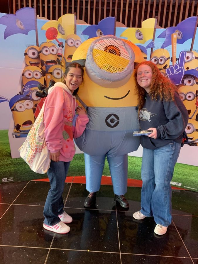 Kylie Hansen ‘23 and Roisin Gaffney ‘23 excitedly pose for a photo with a minion mascot, eager to watch Minions: Rise of Gru in theaters.